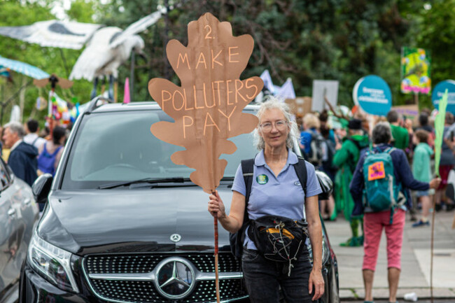 a-woman-is-holding-a-placard-make-polluters-pay-in-front-of-suv-luxury-car-in-london-uk